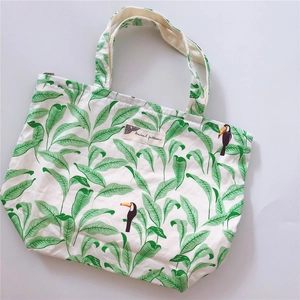 Detail of canvas handbag featuring tropical green leaf and toucan bird prints