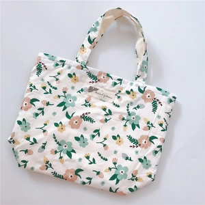 Close-up of floral pattern canvas tote bag with woven label and zipper closure
