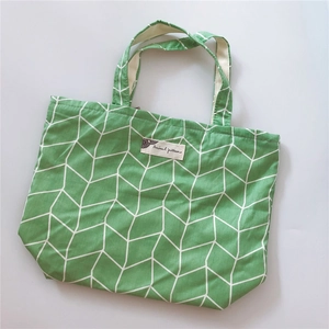 Detail of green cotton tote bag featuring white geometric patterns and woven label