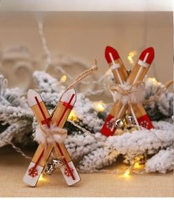Close-up of wooden sled Christmas ornaments with snowflakes and bells on snowy branches