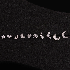 Macro shot of silver zircon stud earrings with celestial star and moon patterns on black foam