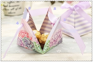 Macro view of purple pyramid gift box with floral pattern and satin ribbon detail