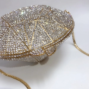 Close-up of golden diamond-shaped evening clutch bag with crystal pavé and metal chain
