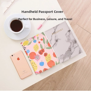 Detail view of pink fruit print and white marble PU leather passport covers on a desk