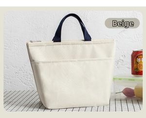 Close-up of beige canvas lunch bag featuring blue handles and a front storage pocket