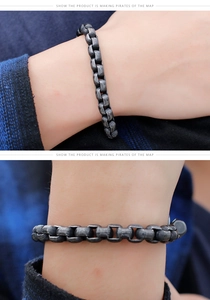 Detail shot of vintage silver dumbbell charm bracelet on wrist with square link chain