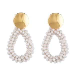 Détail de boucles d'oreilles en perles de cristal blanc en forme de goutte et métal doré