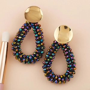 Détail de boucles d'oreilles en perles de cristal colorées sur fond rose avec un pinceau