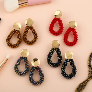 Gros plan de quatre boucles d'oreilles en perles goutte de diverses couleurs sur rose