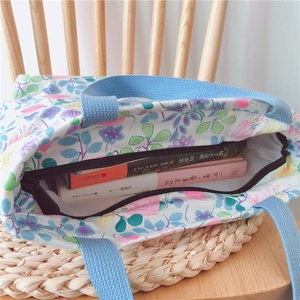 Detailansicht der Blumen-Stofftasche mit Reißverschluss und blauen Webgriffen im Fokus