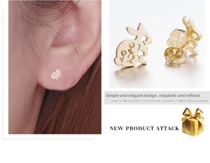 Détail de boucles d'oreilles lapin doré ajouré avec motif floral et rendu porté