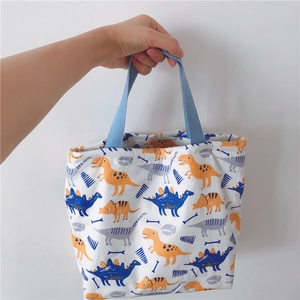 Detail der Canvas-Lunchtasche mit bunten Dinosaurier-Prints und blauen Tragegriffen