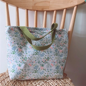 Blumige Baumwoll-Lunchtasche mit kleinen Blüten auf einem rustikalen Holzstuhl