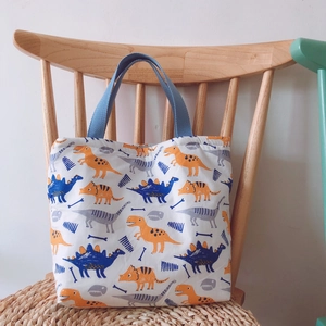 Detail des Dinosaurier-Aufdrucks auf Baumwolltasche mit blauen Webgriffen