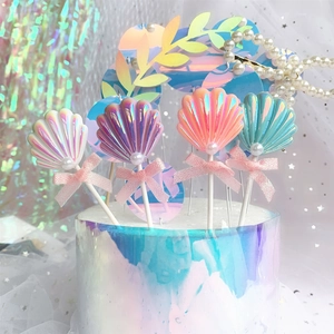 Detailed view of iridescent shell cake toppers with pearls and pink bows for party decor