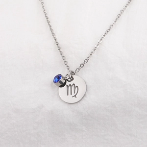 Detailed close-up of Virgo zodiac necklace with a blue birthstone on white fabric