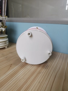 Detail view of the white and pink carousel music box base with three sturdy support feet