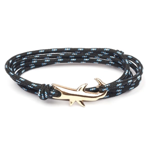 Detailed macro view of a gold shark-shaped anchor clasp on blue and black braided cord