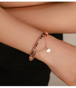 Detail of rose gold bangle featuring Roman numerals, diamonds and heart charm on wrist