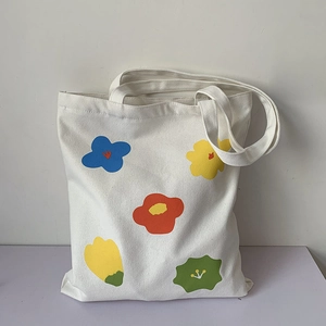 Dettaglio di una borsa tote in tela bianca con motivi floreali astratti colorati dipinti a mano