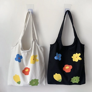 Dettaglio di borse tote in tela bianche e nere con stampe floreali colorate minimaliste
