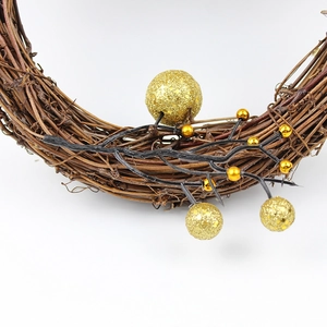 Close-up of Christmas wreath featuring natural vine texture and gold glitter ornaments