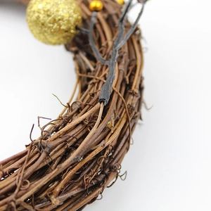 Close-up of brown natural rattan wreath with glitter gold berry and branch details