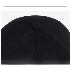 Detail of the stitched top button and six-panel crown on a black cotton baseball cap