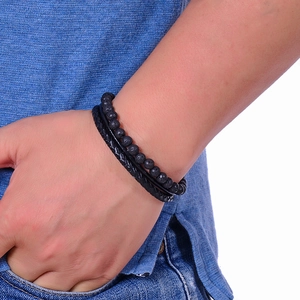 Men's stackable black lava stone beads and braided leather bracelet on a male wrist