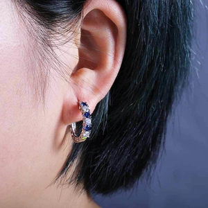 Silver hoop earrings with alternating blue and white cubic zirconia on female model