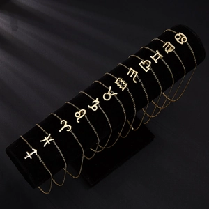 Gold zodiac sign necklaces with rhinestones displayed on a professional black velvet stand