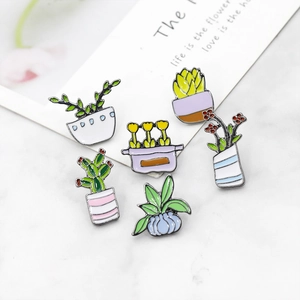 Set of six cartoon cactus enamel pins on white marble background for clothing decoration