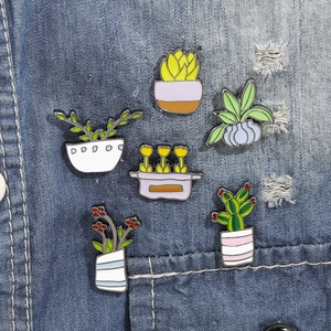 Detail view of 6 colorful enamel plant pins displayed on denim fabric background