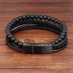 Macro detail of men's multilayer black braided leather and beaded bracelet on wood texture