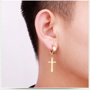 Close-up of gold stainless steel cross dangle earring worn on the earlobe