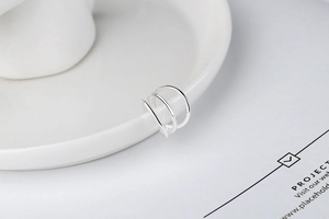 Detailed macro view of minimalist S925 sterling silver three-layer ear cuff on a white plate