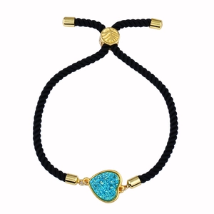 Detalle de pulsera ajustable de cordón trenzado negro con dije de corazón azul drusa