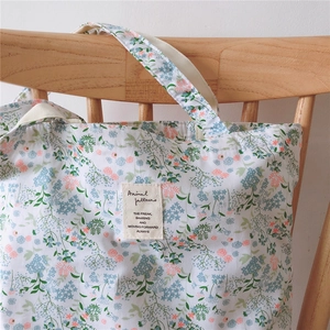 Detail of floral canvas tote bag featuring delicate blue and pink petals and text label