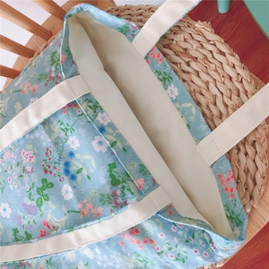Close-up of light blue floral cotton tote bag with sturdy off-white canvas handles