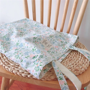 Detail of floral cotton tote bag with delicate blue and orange prints on a wooden chair