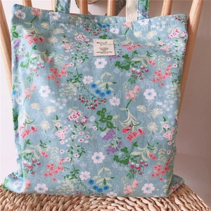 Detailed shot of a floral canvas tote bag with a vintage tag on a rustic wooden chair
