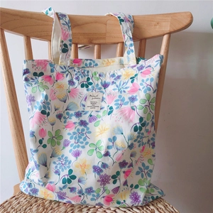 Detail of floral print canvas tote bag featuring botanical patterns on a wooden chair