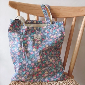 Detailed close-up of a floral cotton tote bag hanging on a wooden chair in soft light