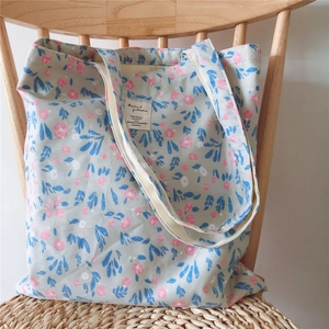 Floral cotton tote bag with pink flowers resting on a vintage wooden chair