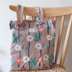 Detail of floral tote bag with daisy pattern hanging on a wooden chair in soft light