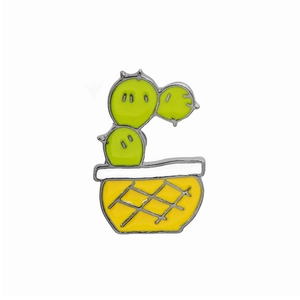 Macro detail of enamel cactus pin in yellow checkered pot with silver metallic edges
