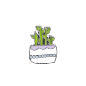 Detailed view of enamel bamboo plant brooch with silver metal and green plant design