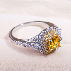 Dettaglio macro di anello con zircone giallo taglio cushion e doppio halo su velluto