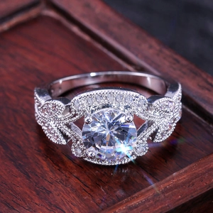 Elegant silver leaf wedding ring with large round solitaire diamond on a wooden tray