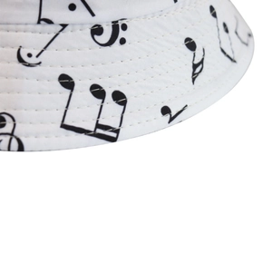 Reversible white fisherman bucket hat with black music note pattern and detailed stitching